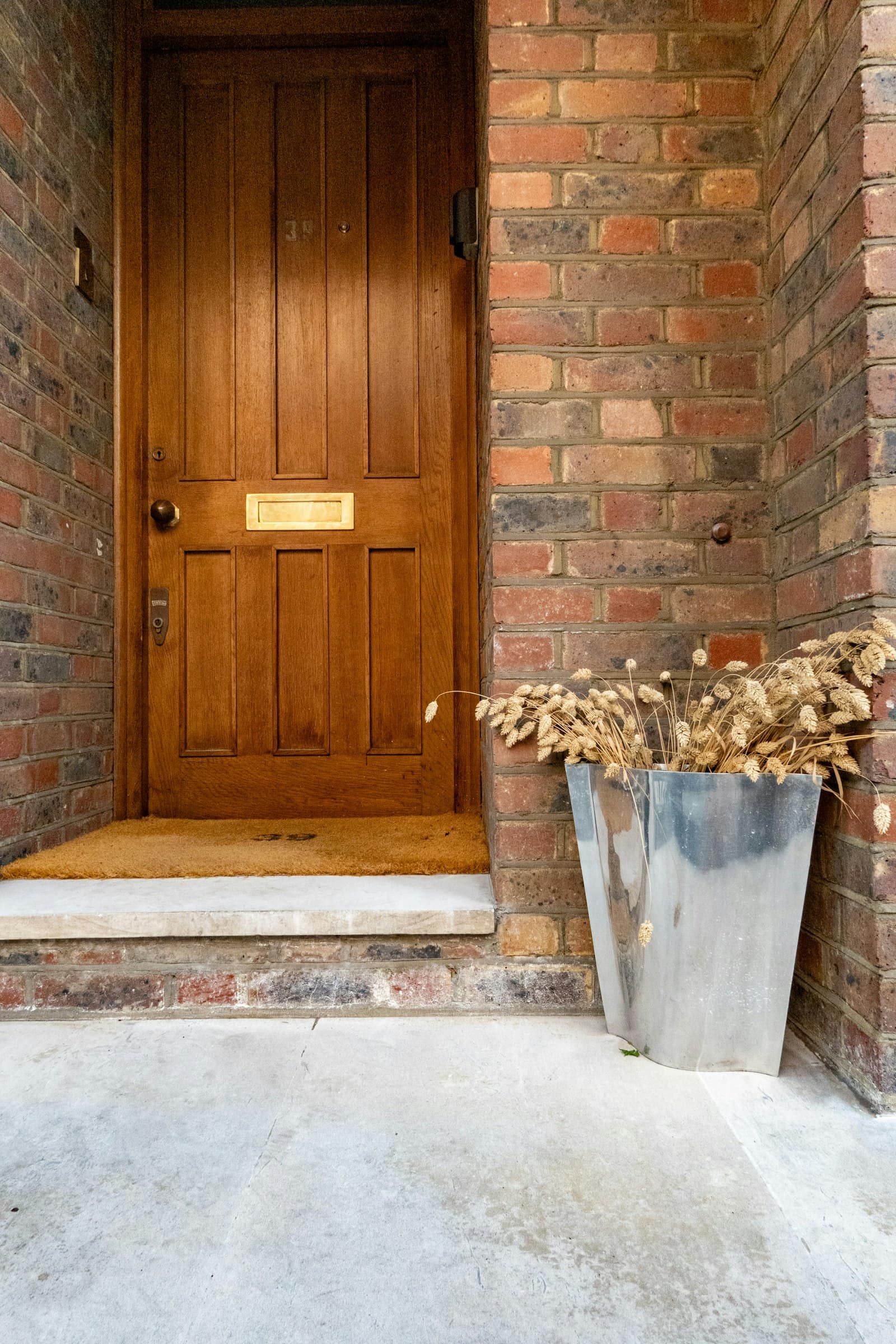 Wooden front door with a metal planter at the entry