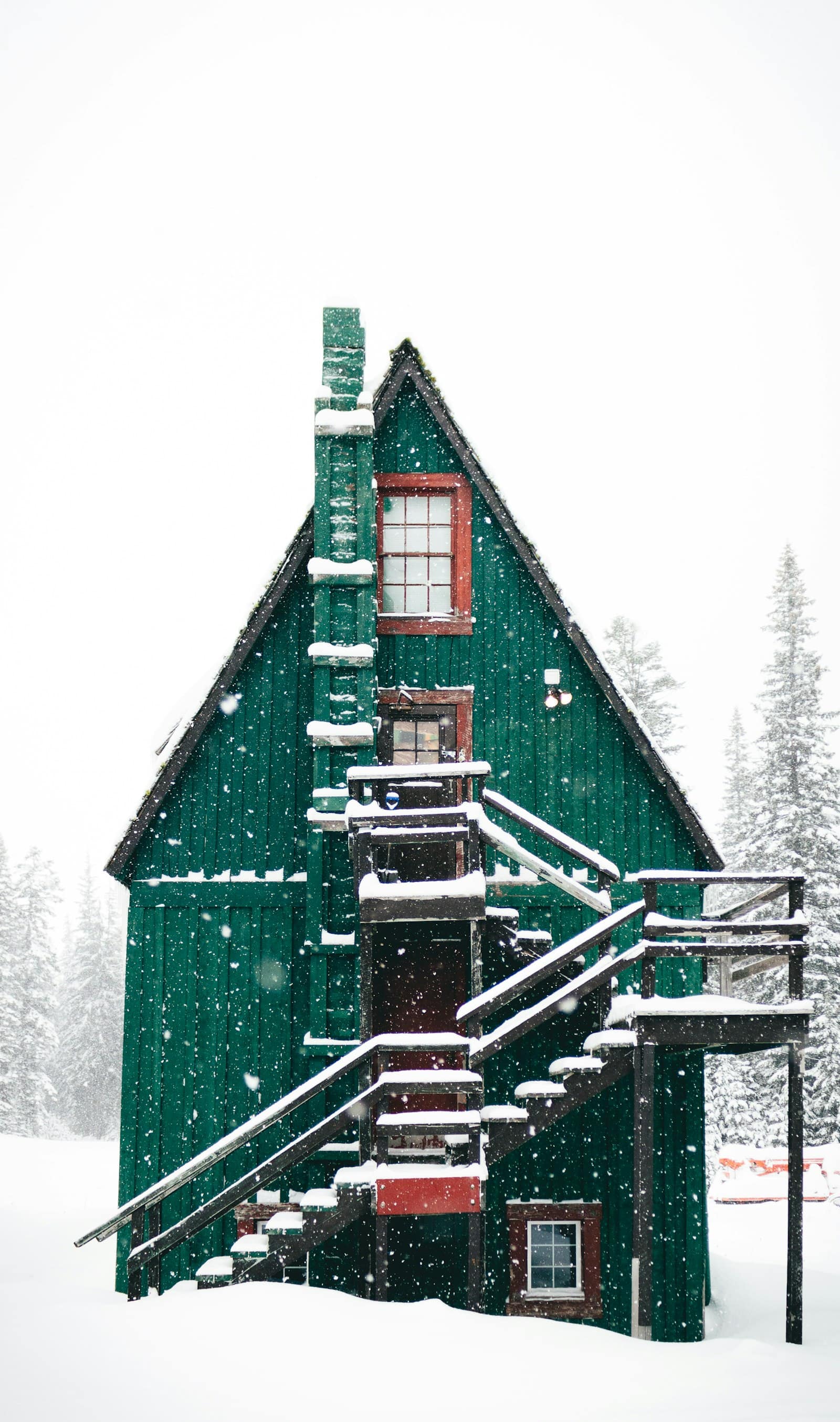 Snow falling over a green wooden house in winter