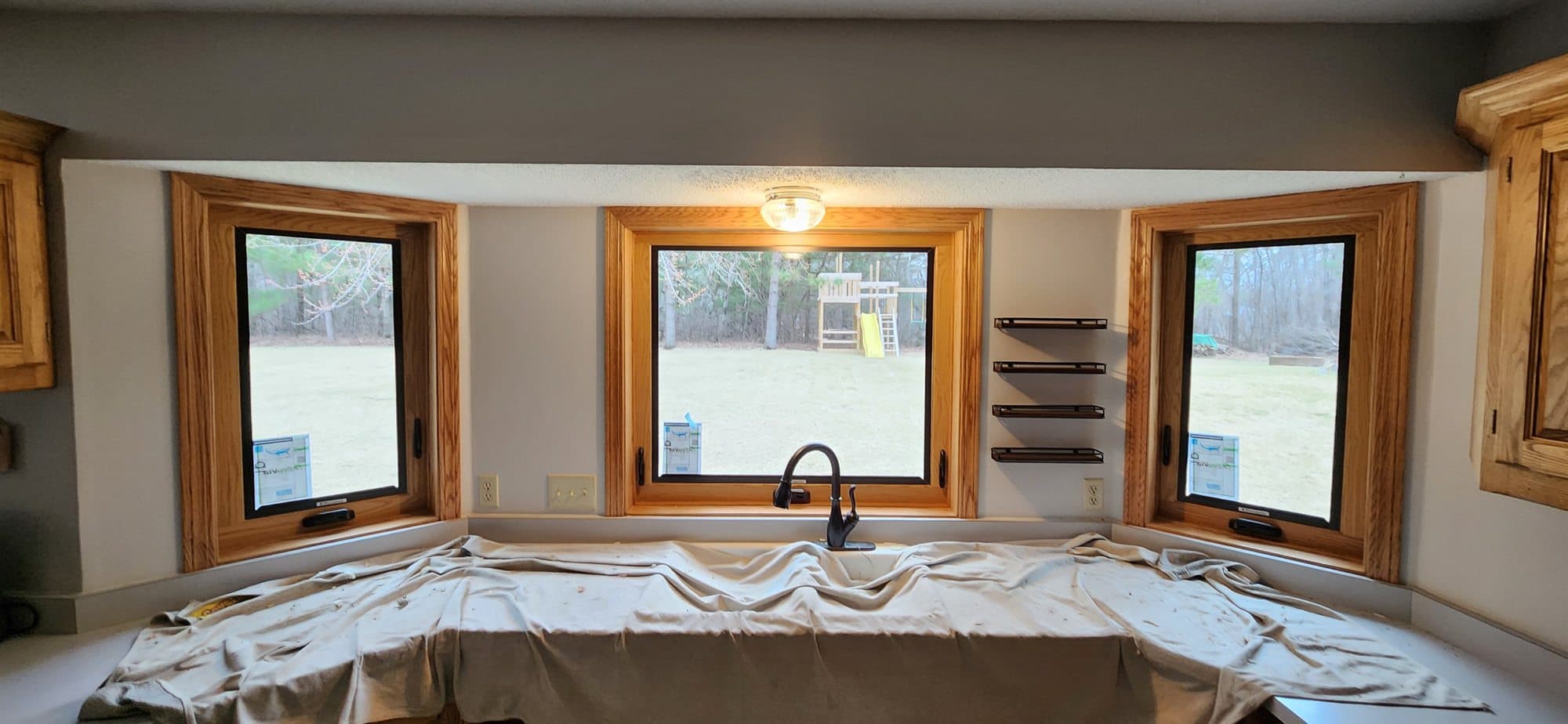 New black casement windows with oak trim installed above a kitchen sink by JMB Builders
